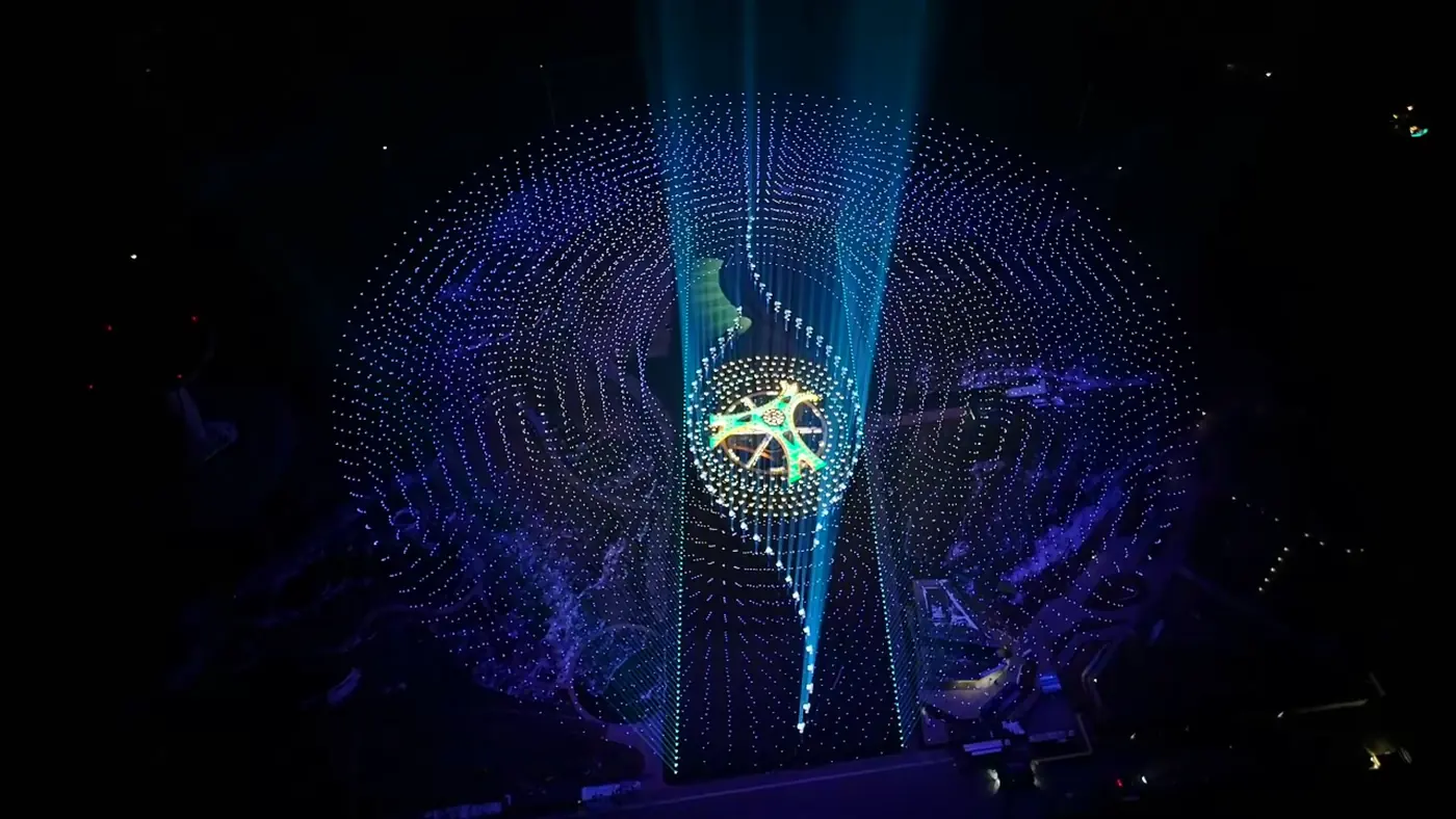 Dome of illuminated drones with an ornamental golden figure at its centre during a night festival